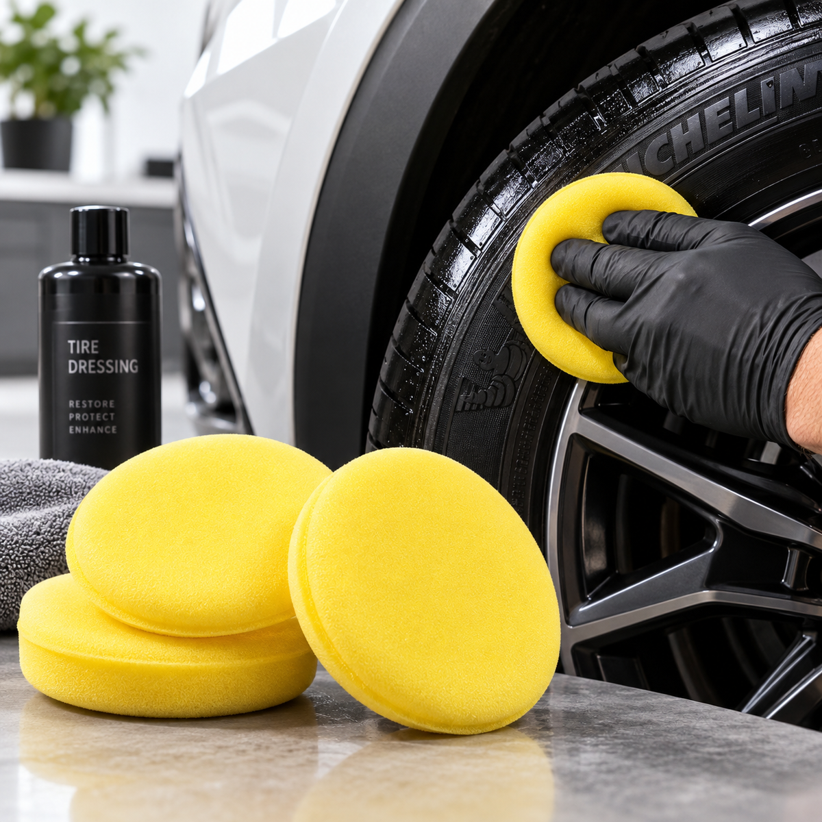 Yellow detailing applicator pads being used on a vehicle tire